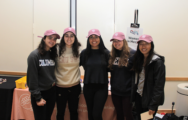 Students in pink hats at the Women in MechE table at an event. 