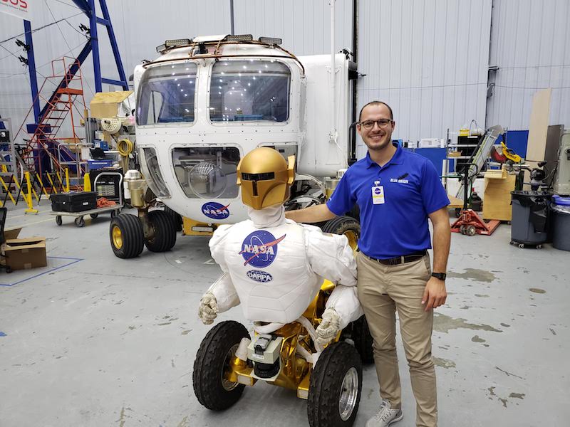 Larry Papincak at NASA posing beside a model of a moon vehicle. 