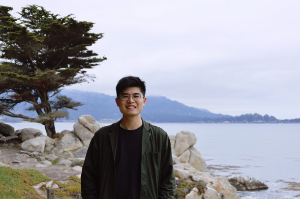 Liwei Wang standing in front of mountains, a lake, and tree