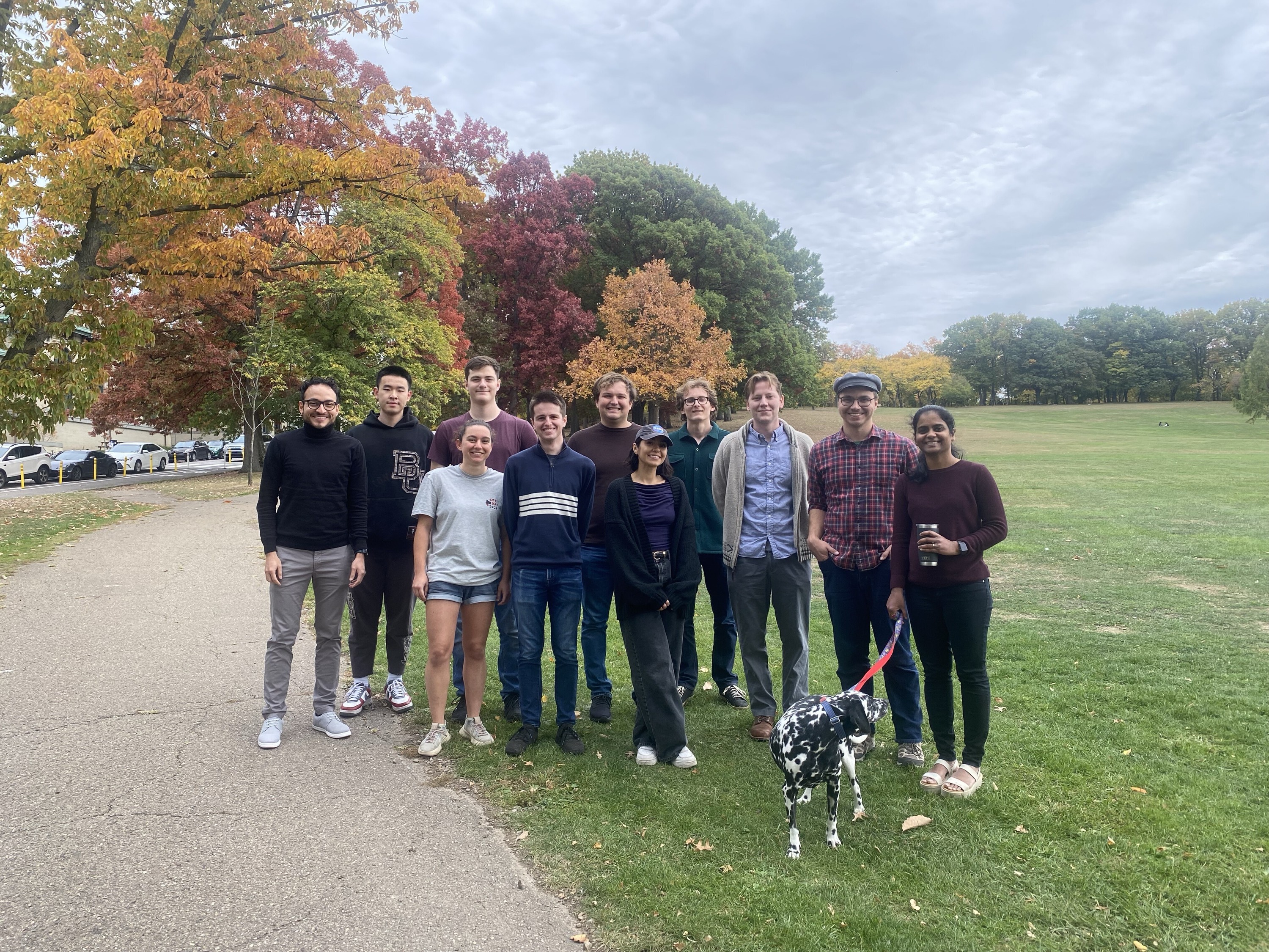 research group standing together outside in front of fall leaves